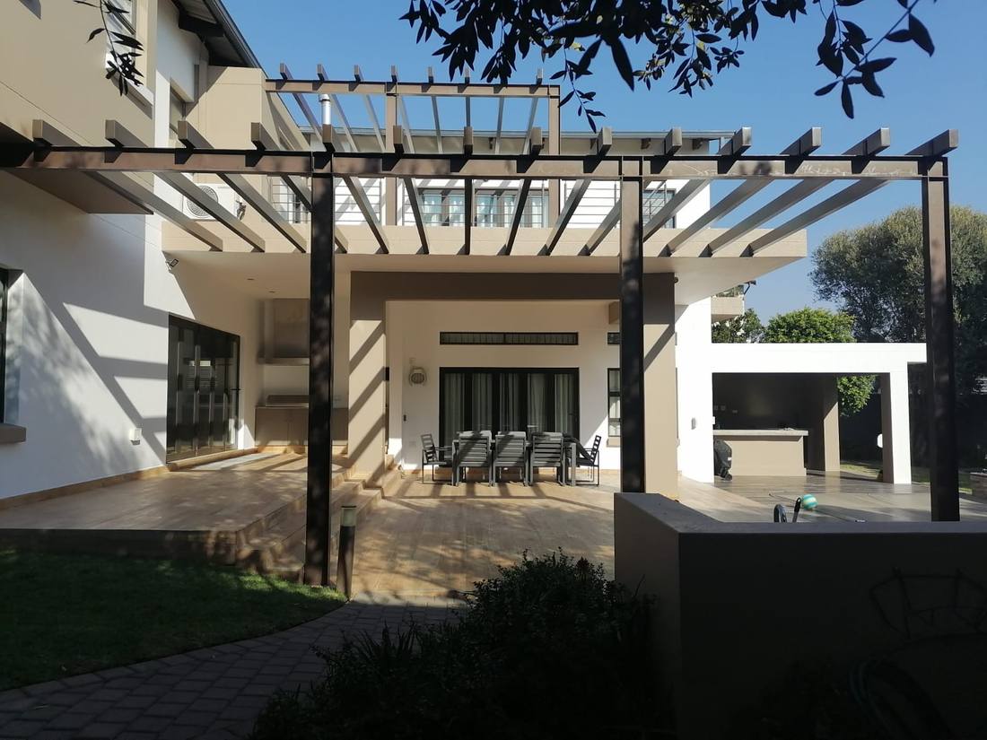 The pergola running back to the balcony edge beside the outdoor kitchen