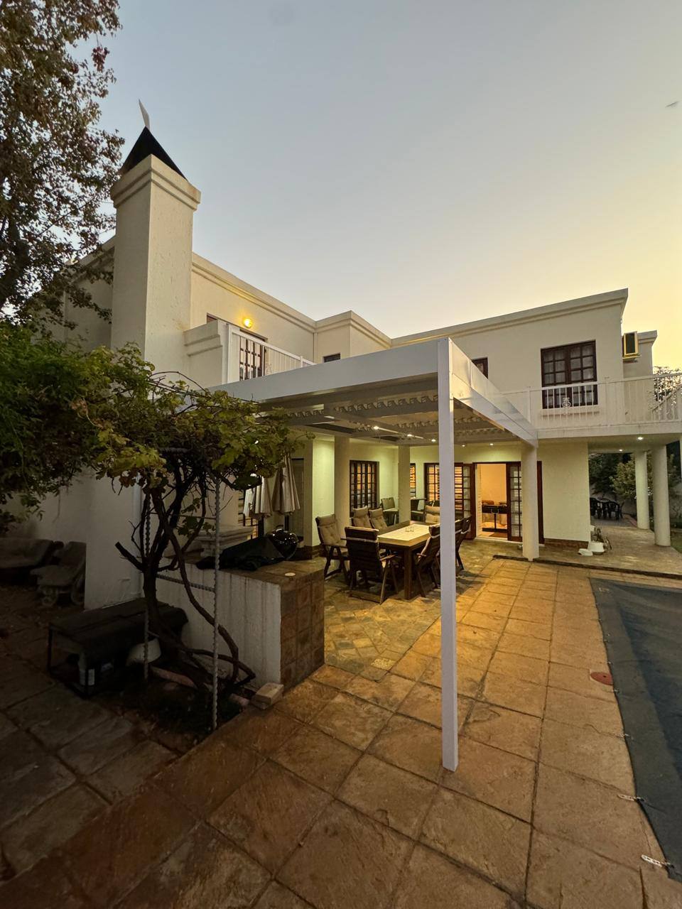 The Benoni patio at dusk, downlights on beneath the white louvre
