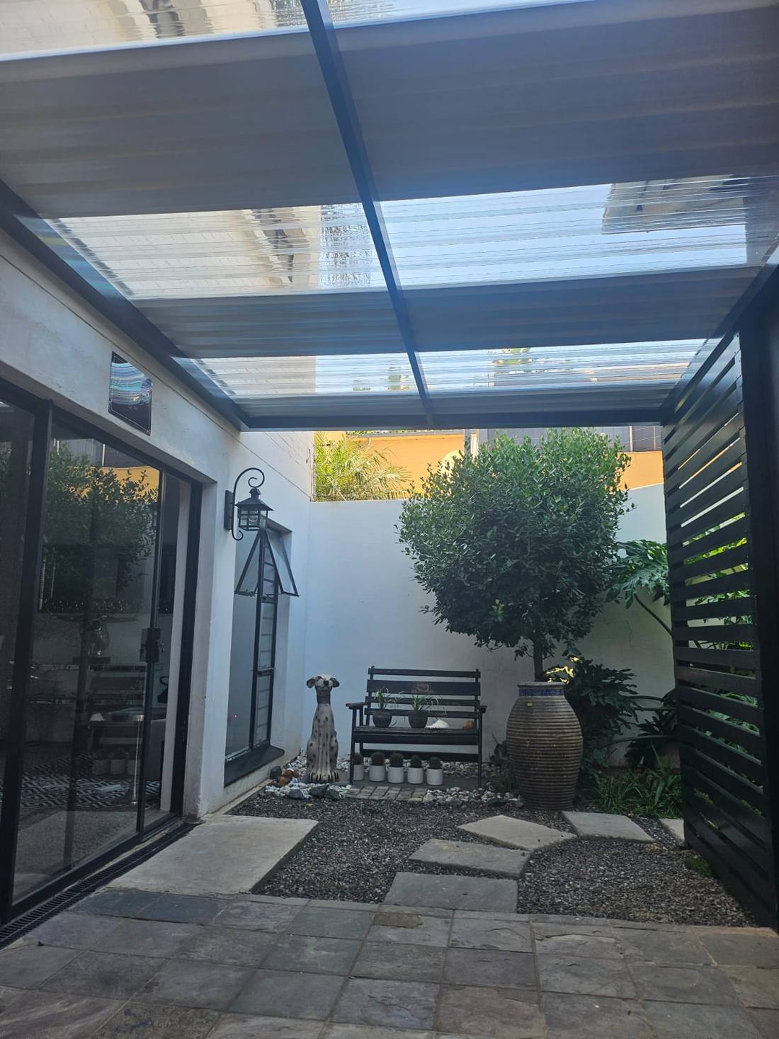 Aluminium slat screen closing the open end of the polycarbonate courtyard